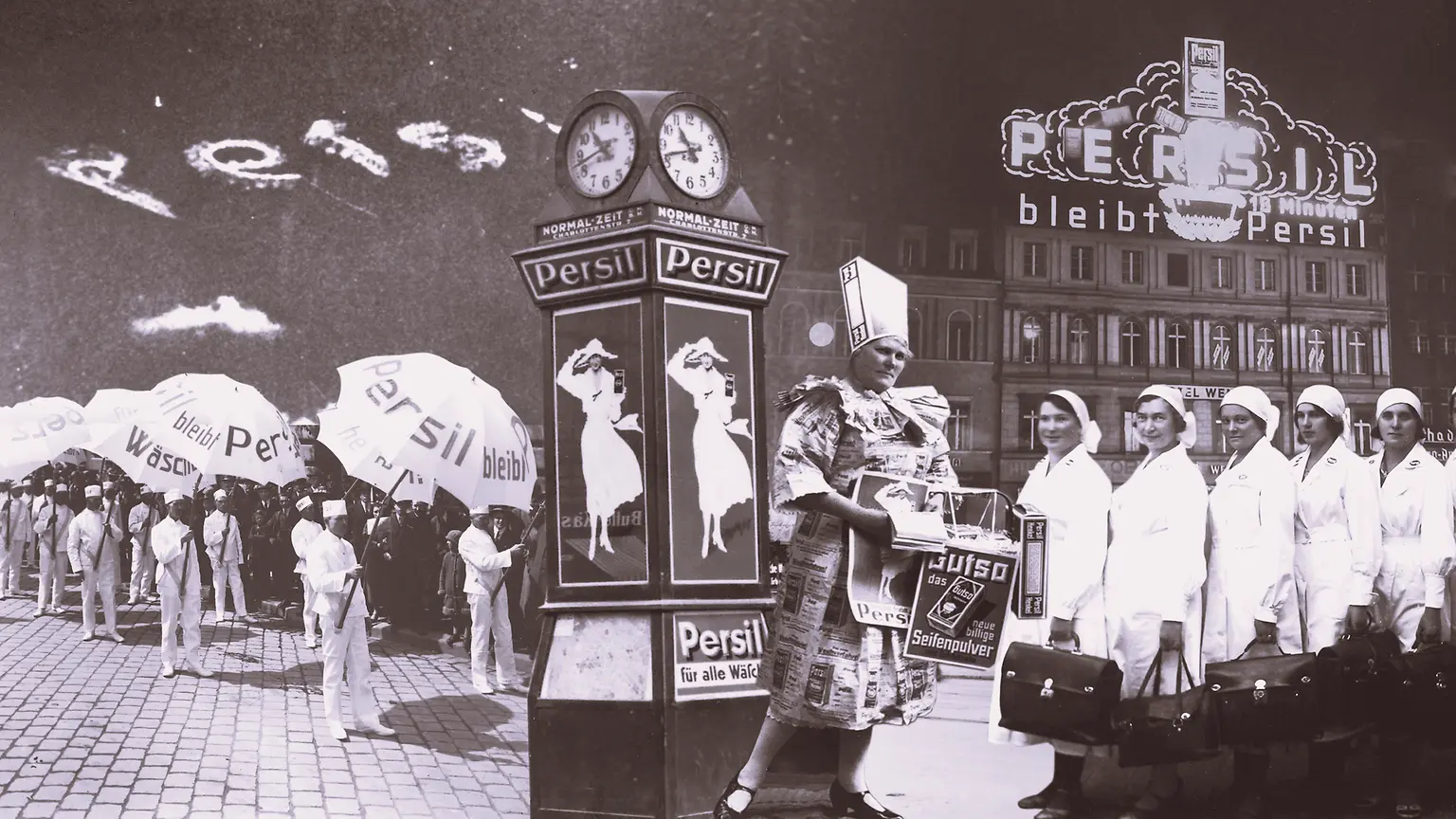 Collage publicitario vintage de Persil en el que aparecen personas con paraguas de la marca, un reloj decorativo con carteles y un edificio con el letrero iluminado de Persil al fondo.