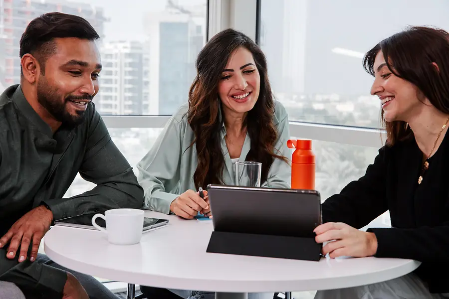 Tres compañeros de trabajo sentados juntos en una mesa.