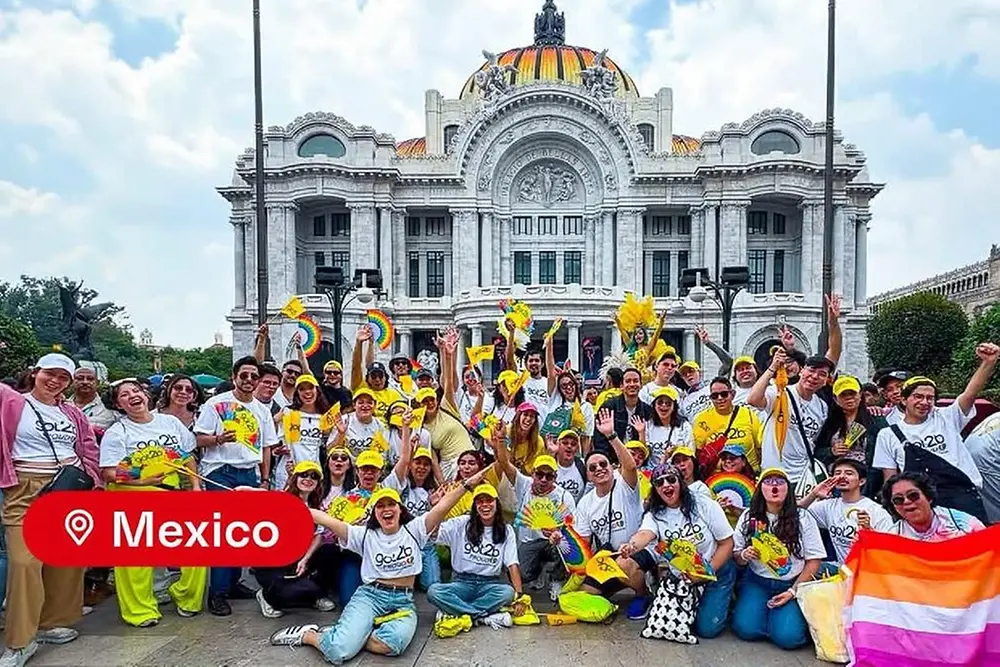Collage de dos fotos de una celebración del Orgullo en México. La foto superior muestra a un gran grupo de participantes caminando al aire libre en un desfile por una zona de la ciudad con edificios de gran altura al fondo. Muchos participantes llevan camisas blancas y sombreros de color amarillo brillante, y algunos llevan paraguas y accesorios con temática de arcoíris. La foto inferior muestra a un grupo grande sosteniendo banderas de arcoíris y carteles coloridos. En la esquina inferior izquierda de la imagen aparece una etiqueta de ubicación que dice “México”.