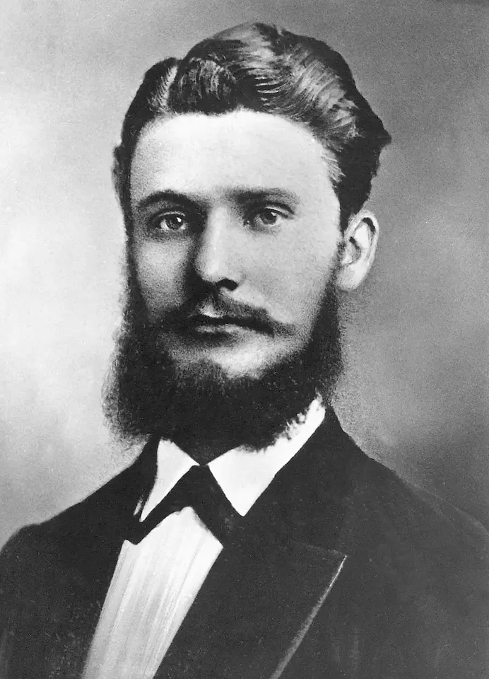 Retrato histórico en blanco y negro de Fritz Henkel con traje formal, barba completa y cabello cuidadosamente peinado.